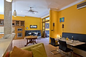 A dining area with a booth seating arrangement, a kitchen with granite countertops, and a dining table set for four. - Sunset villa (Ungasan)
