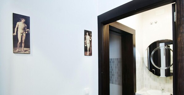Un baño con un espejo grande, un lavamanos y dos obras de arte enmarcadas en la pared.