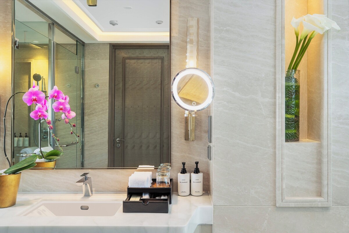 Un baño moderno con un espejo grande, un lavamanos y una orquídea en maceta.