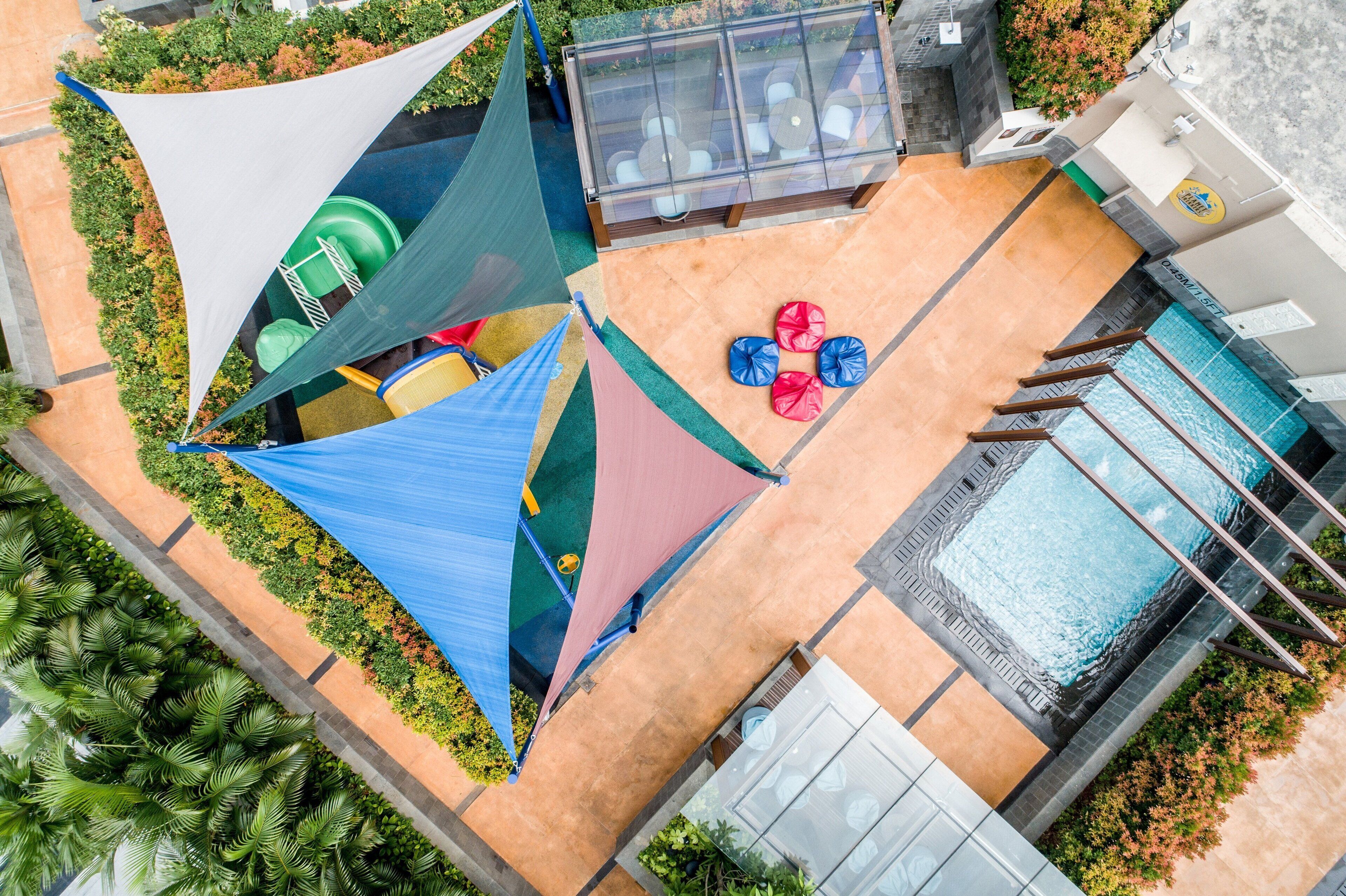 A rooftop pool area with a glass enclosure, a pool, and a seating area with umbrellas.