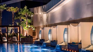 Un área de piscina con sillones reclinables y una pequeña cascada.
