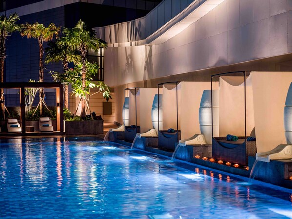 Un área de piscina con sillones reclinables y una pequeña cascada.