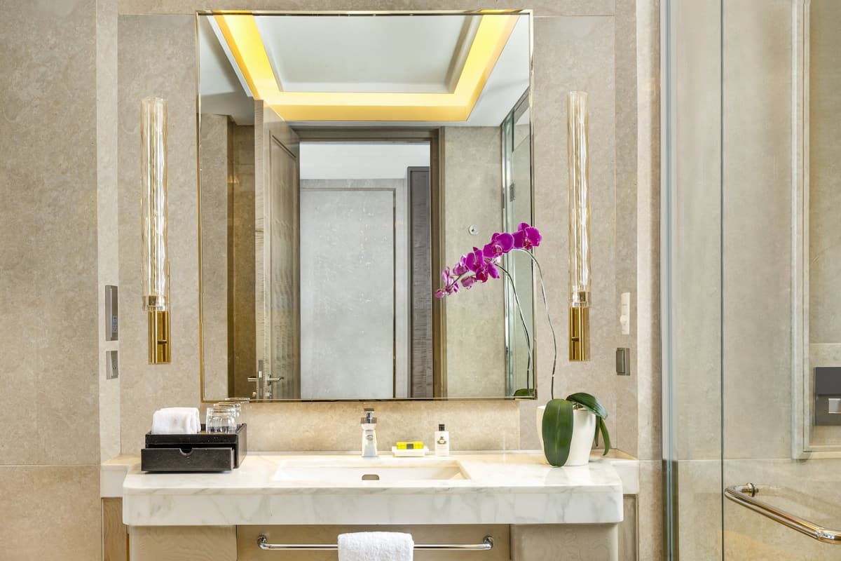 Un baño moderno con un espejo grande, un lavabo y una zona de ducha.
