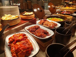 Ein Buffet mit verschiedenen Speisen, darunter Braten, Gemüse und weitere Gerichte.