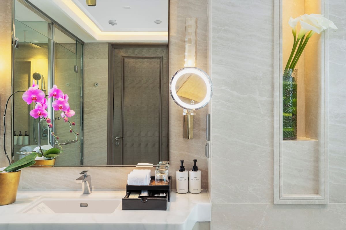 Un baño moderno con un espejo grande, un lavamanos y una orquídea en maceta.