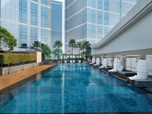 A modern indoor pool with a tiled floor, surrounded by lounge chairs and palm trees. - InterContinental Jakarta Pondok Indah by IHG (Jakarta)
