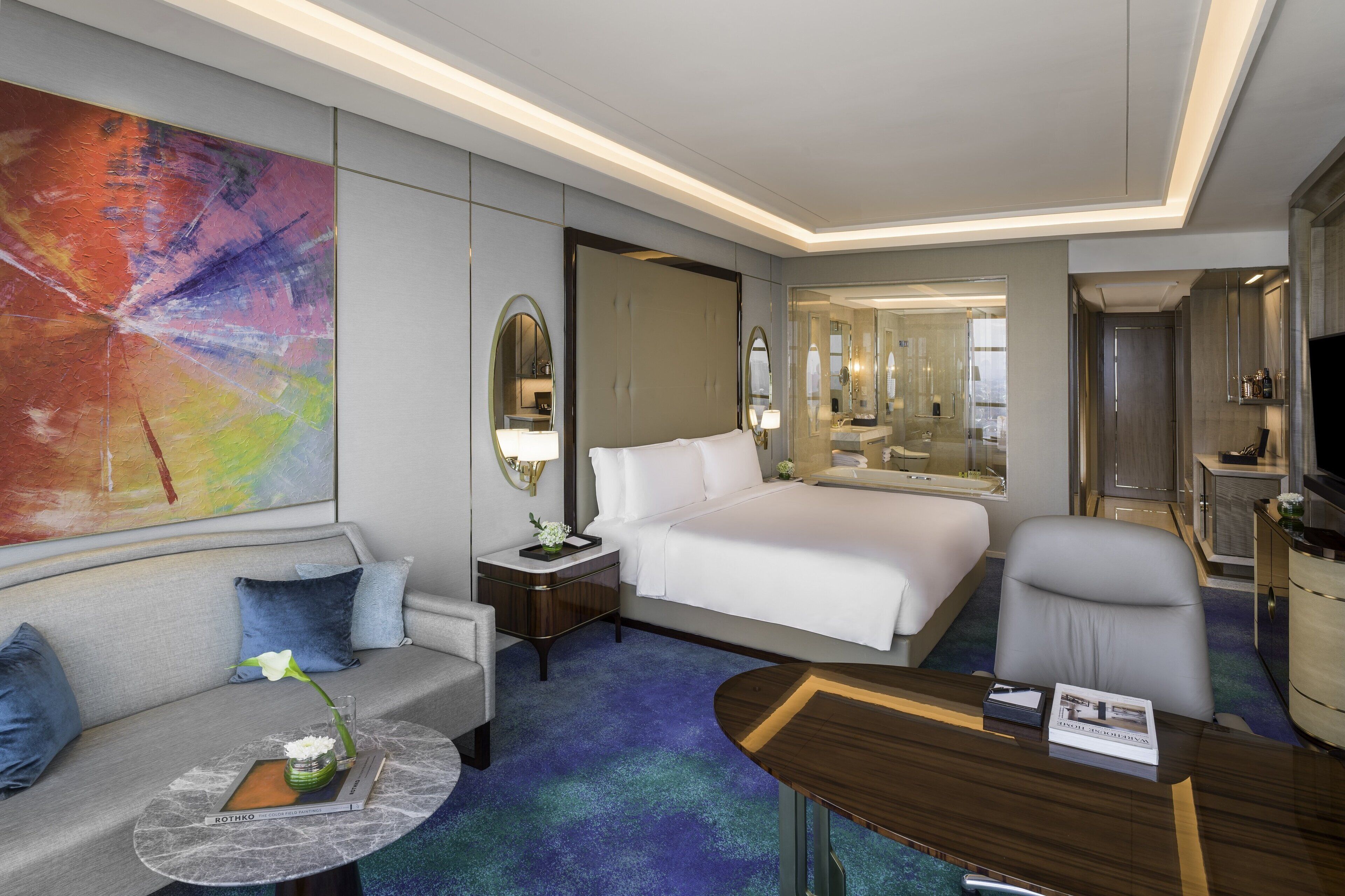 Ein Hotelzimmer mit einem großen Bett, einer Sitzecke, einem Schreibtisch und einem Spiegel.