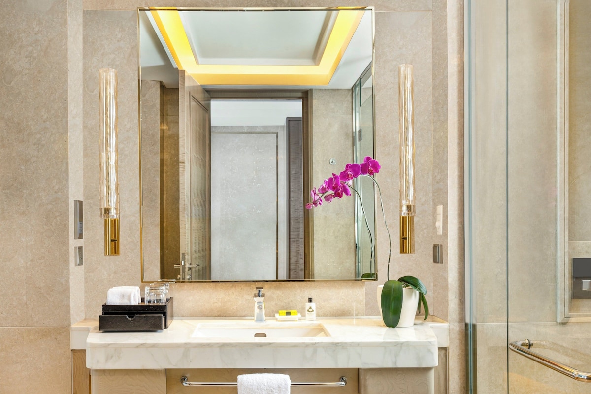 Un baño moderno con un espejo grande, un lavabo y una zona de ducha.