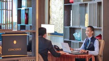Una reception hotel con un cartello che indica il servizio concierge, un computer portatile e un telefono.