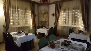 Un comedor con mesas dispuestas para cuatro comensales, cada una con mantel blanco, sillas verdes y diversos elementos de comedor.
