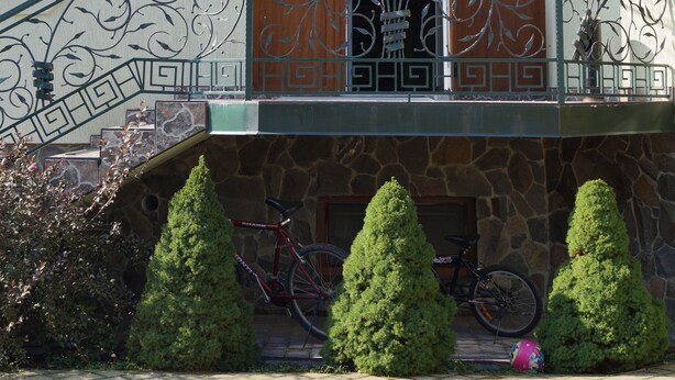 Un edificio de fachada de piedra, un balcón con barandillas de metal ornamentadas y una bicicleta estacionada afuera.