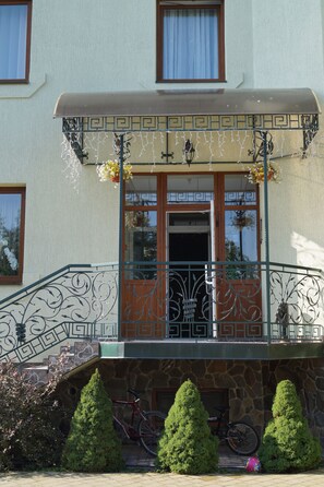 A building with a stone facade, a balcony with ornate metal railings, and a bicycle parked outside. - Hermes Resort Hotel (Truskavets)