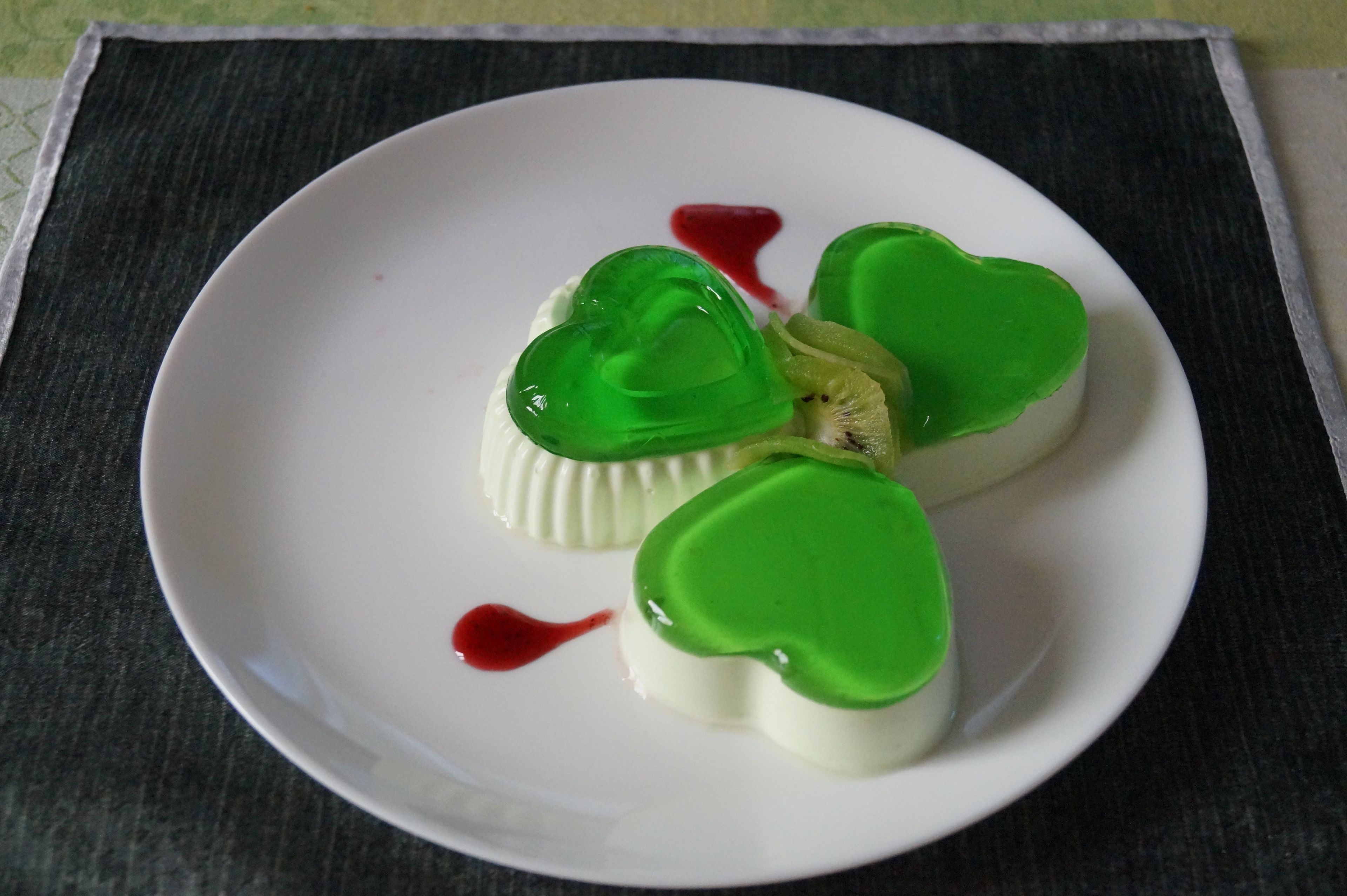 Un plato blanco con postres con forma de corazón y un poco de salsa roja.