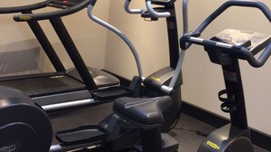 Un gimnasio con cintas de correr, elípticas y una bicicleta estática.