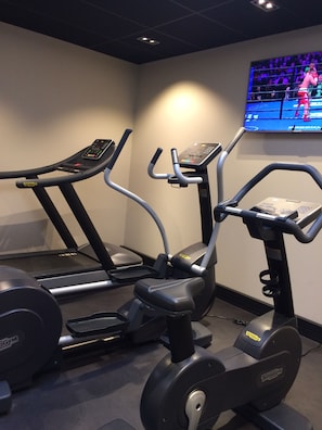 Un gimnasio con cintas de correr, elípticas y una bicicleta estática.