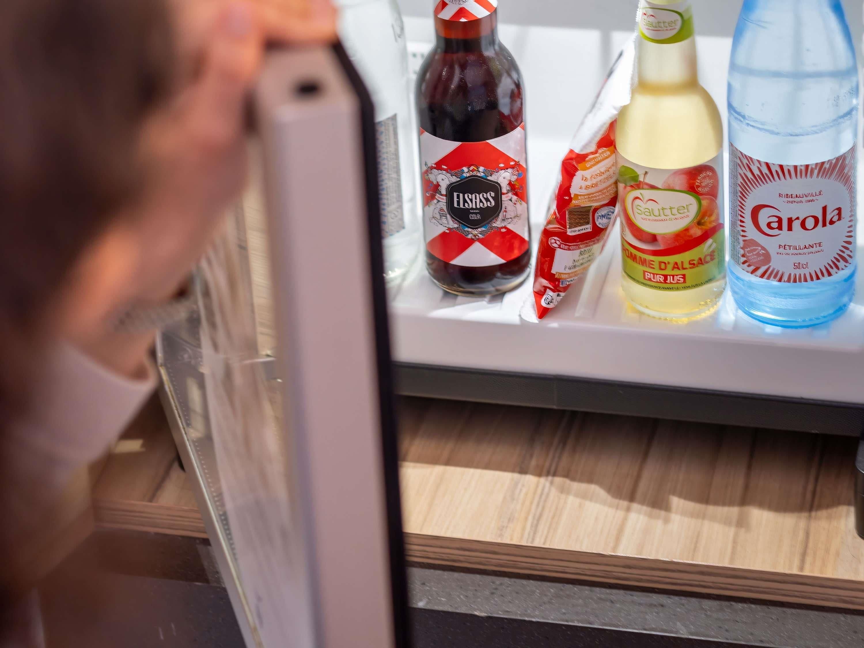 Un refrigerador con diversos alimentos, incluyendo una botella de salsa Elssass, un paquete de mantequilla y una botella de Carola.