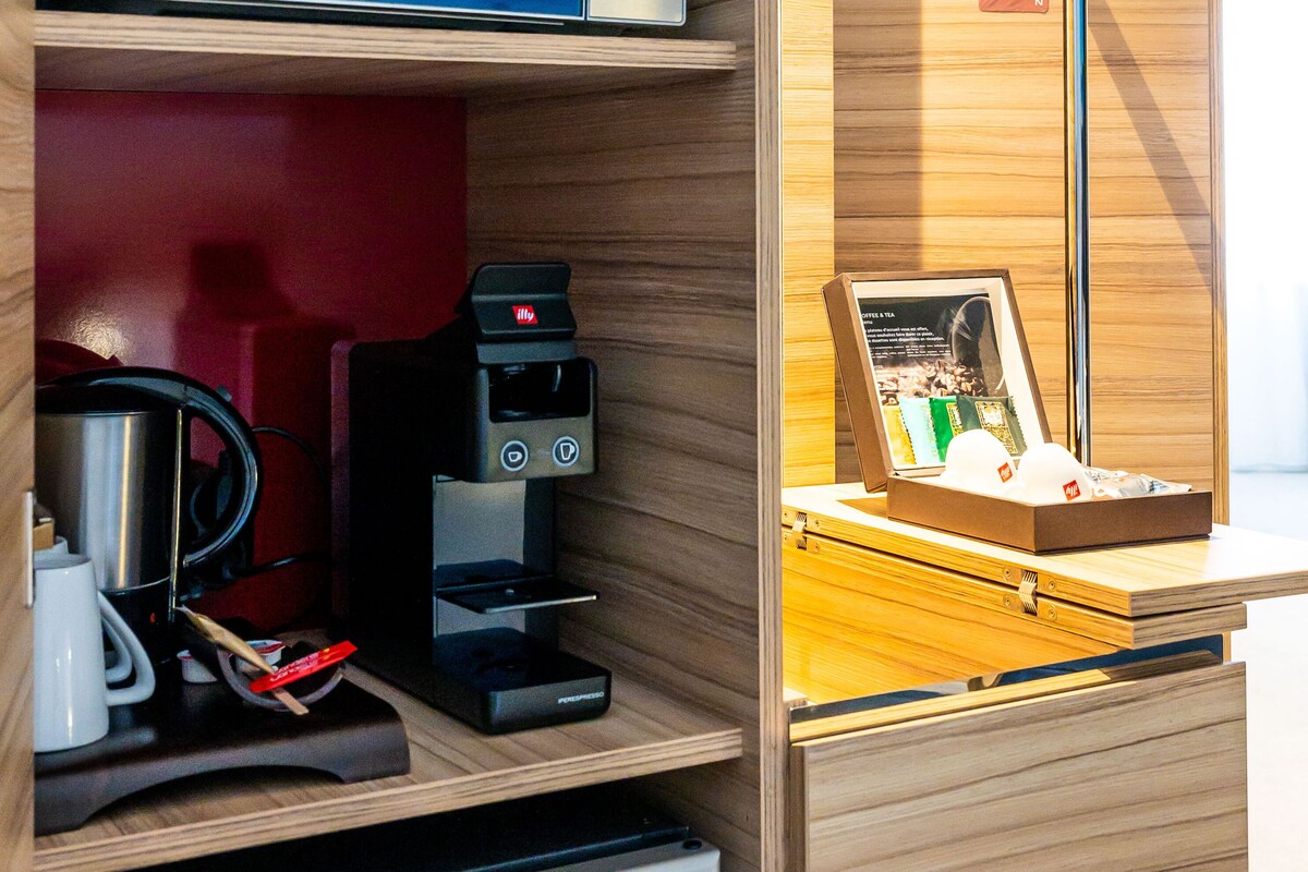 Una kitchenette equipada con microondas, cafetera y refrigerador pequeño.
