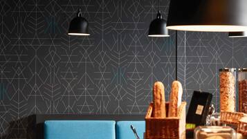 Un interior moderno con patrones geométricos en la pared, un sofá azul y una encimera con pan y una botella de vino.
