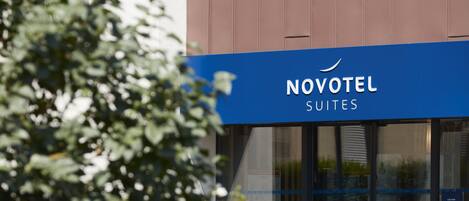 Un letrero de hotel con el nombre "NOVOTEL SUITES" y un toldo azul.