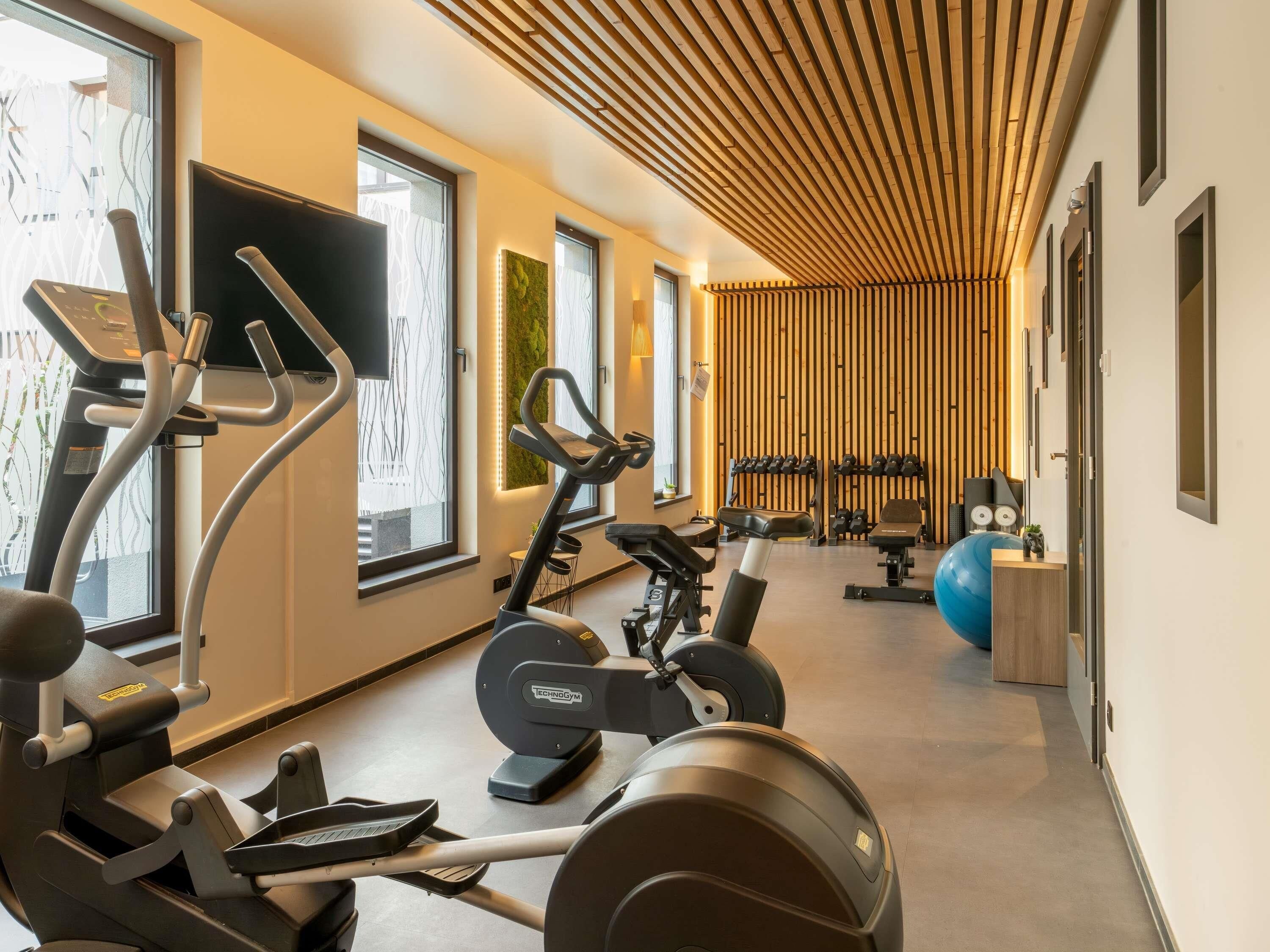 Une salle de sport moderne équipée de machines de cardio, de matériel de musculation et d’un grand ballon d’exercice.