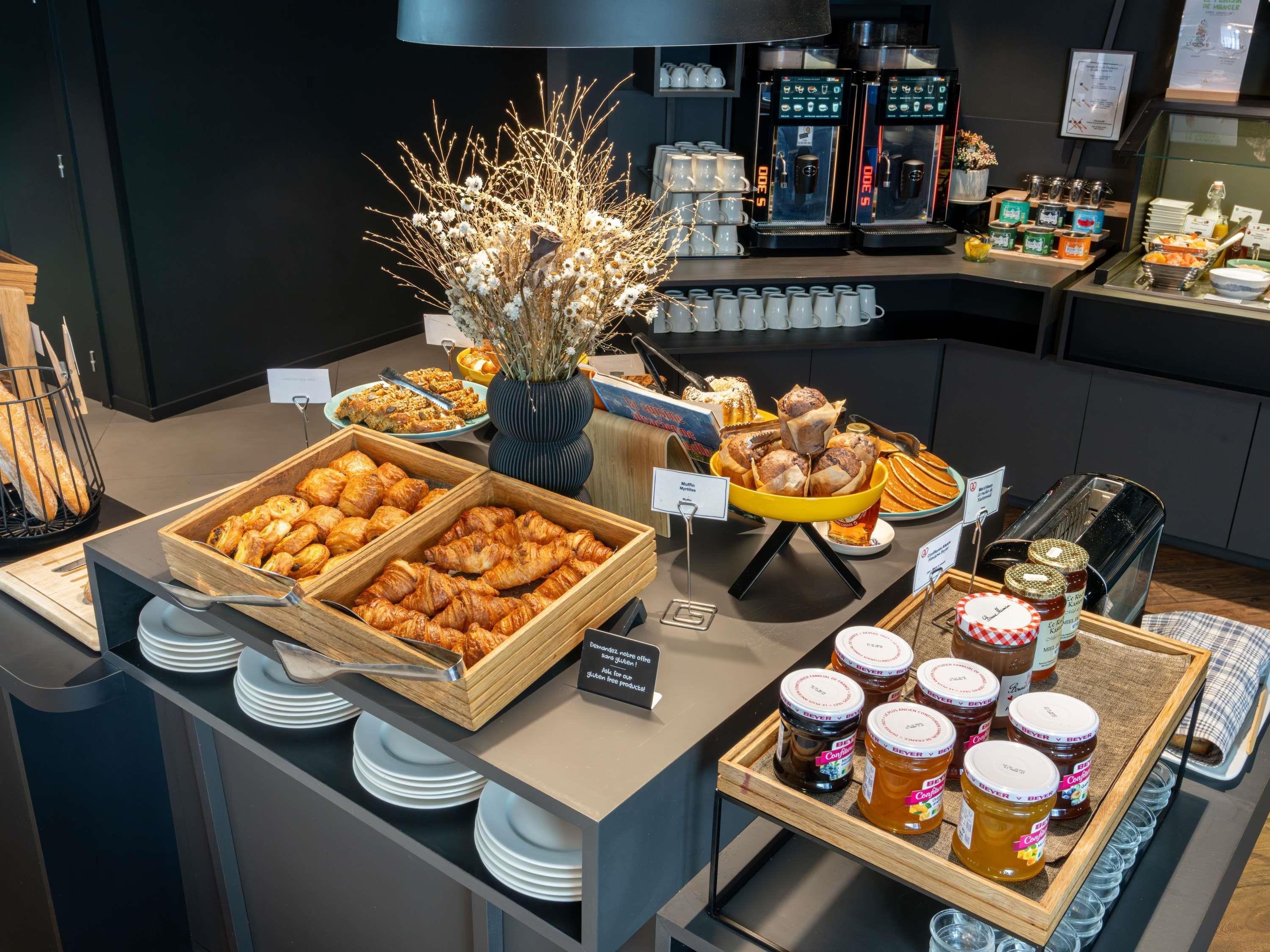 A buffet with various food items, including pastries, bread, and condiments.