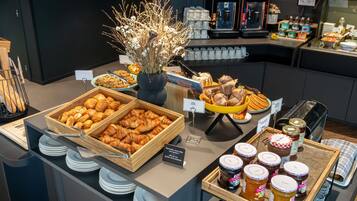 A buffet with various food items, including pastries, bread, and condiments.
