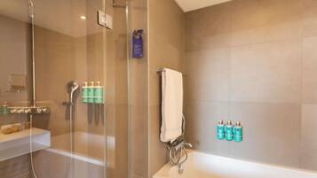 Ein modernes Badezimmer mit einer Glasdusche, einer Badewanne und Pflegeprodukten an der Wand.
