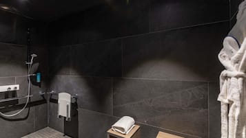 Une salle de bain moderne équipée d’une douche, d’un porte-serviettes et d’un tabouret en bois.