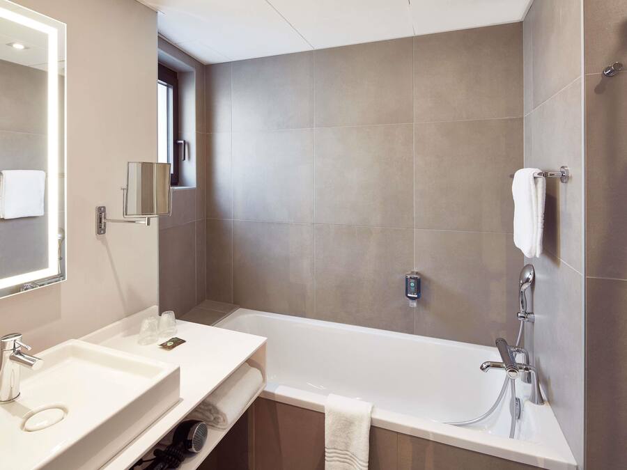 A modern bathroom with a bathtub, a sink, a mirror, and a towel rack.