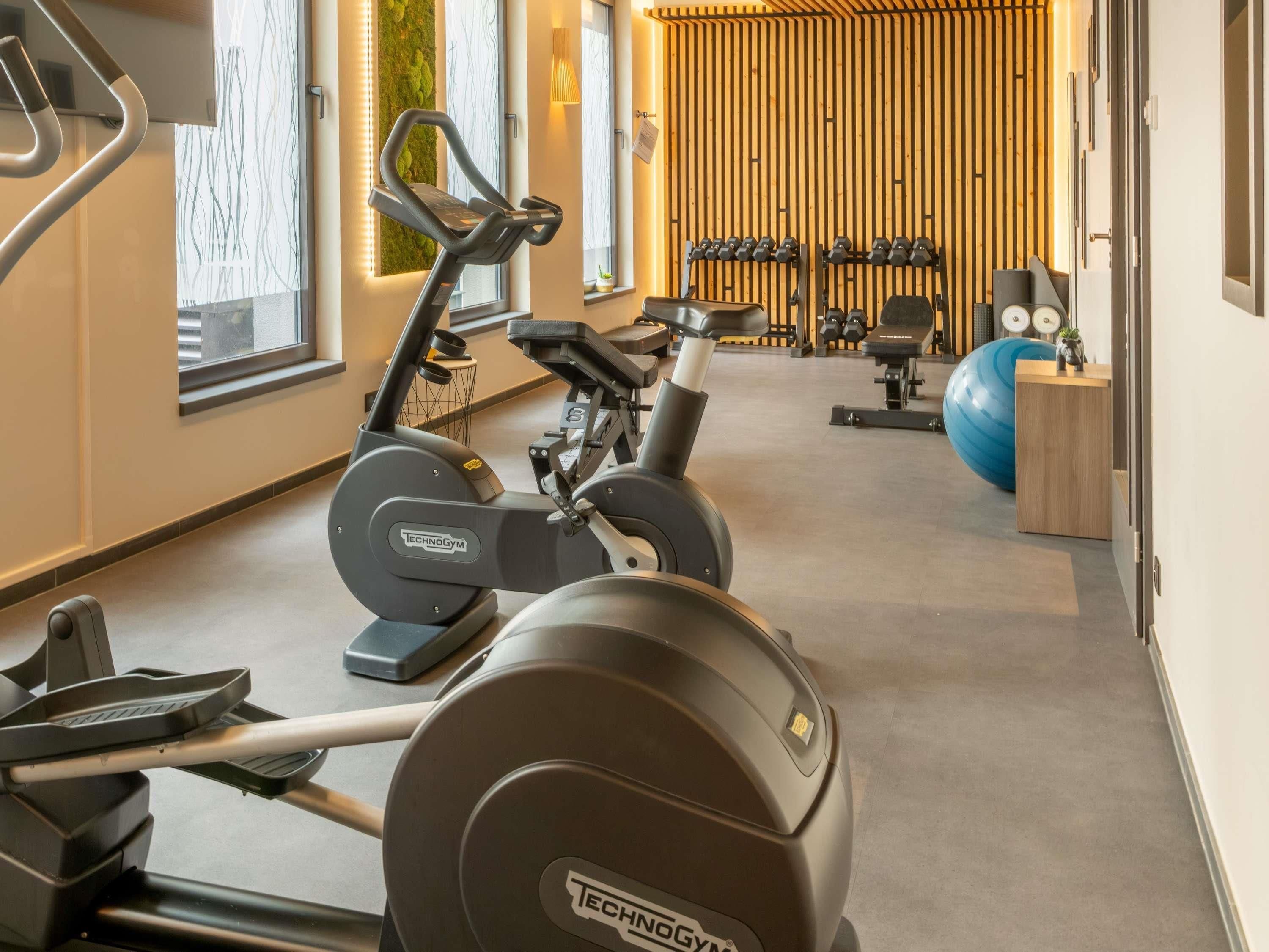 A gym with cardio machines, weightlifting equipment, and a large exercise ball.