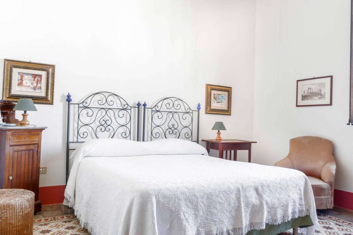 A neatly arranged bedroom with a bed, a chair, a small table, and a cabinet.