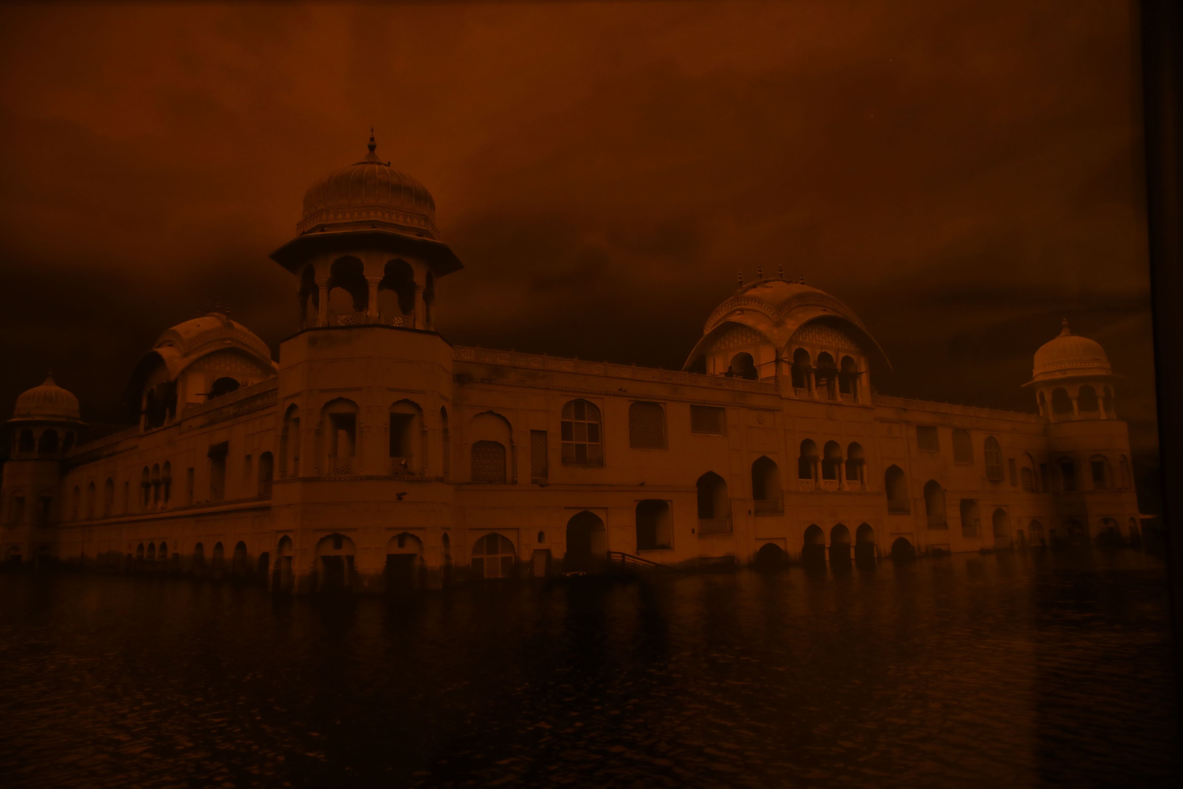 A historic building with multiple domes and arches, situated by a body of water.