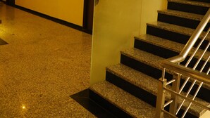 A hotel corridor with a staircase, a sign indicating room numbers, and a door with a mirror. - The Prime Hotel Jaipur (Jaipur)