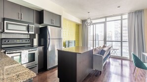 Eine moderne Küche mit Edelstahlgeräten, einer großen Kochinsel und Blick auf die Stadt durch große Fenster.