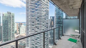 Ein Balkon mit Glasgeländer mit Blick auf eine Stadtlandschaft und moderne Hochhäuser.