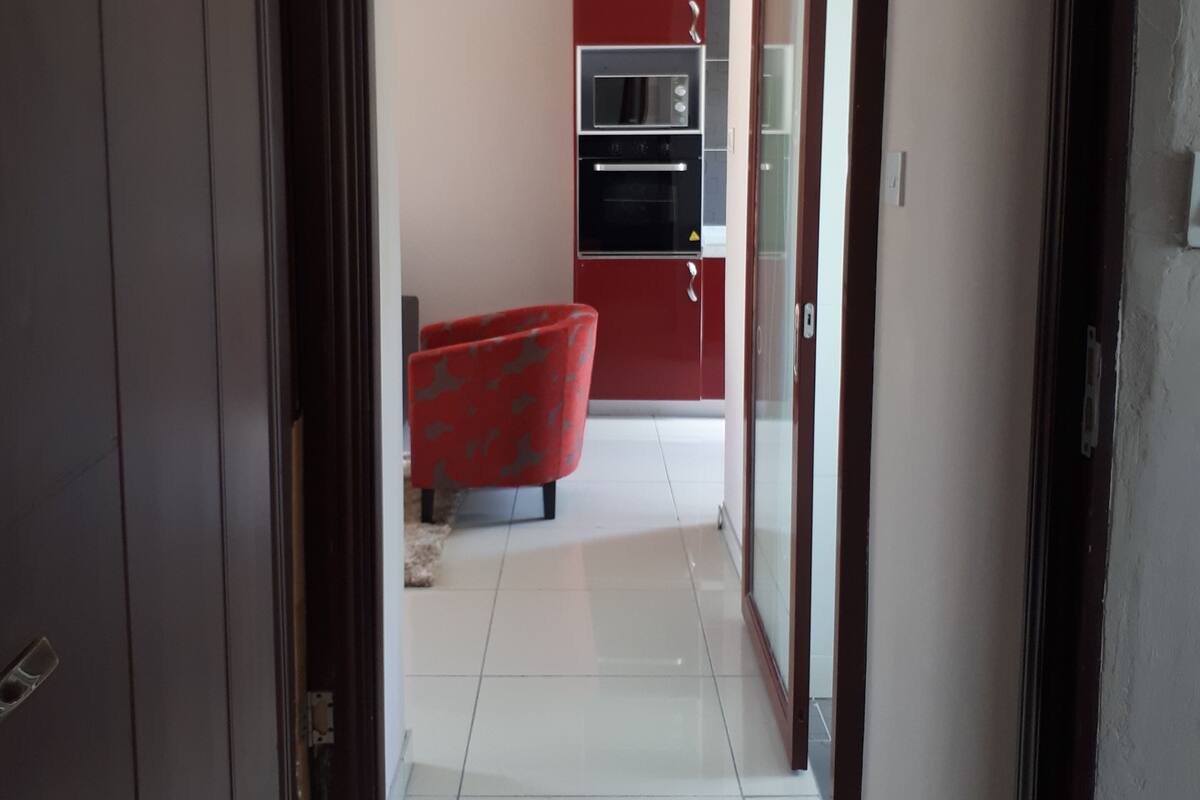 A hallway leading to a kitchen with red cabinets, a microwave, and an oven.