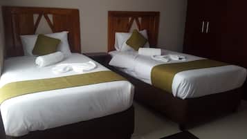 Two single beds with wooden headboards, white linens, and green throw pillows.