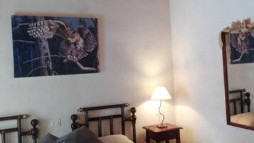 Ein Schlafzimmer mit Bett, Kissen, einer Nachttischlampe, einem Wandbild und einem Spiegel.