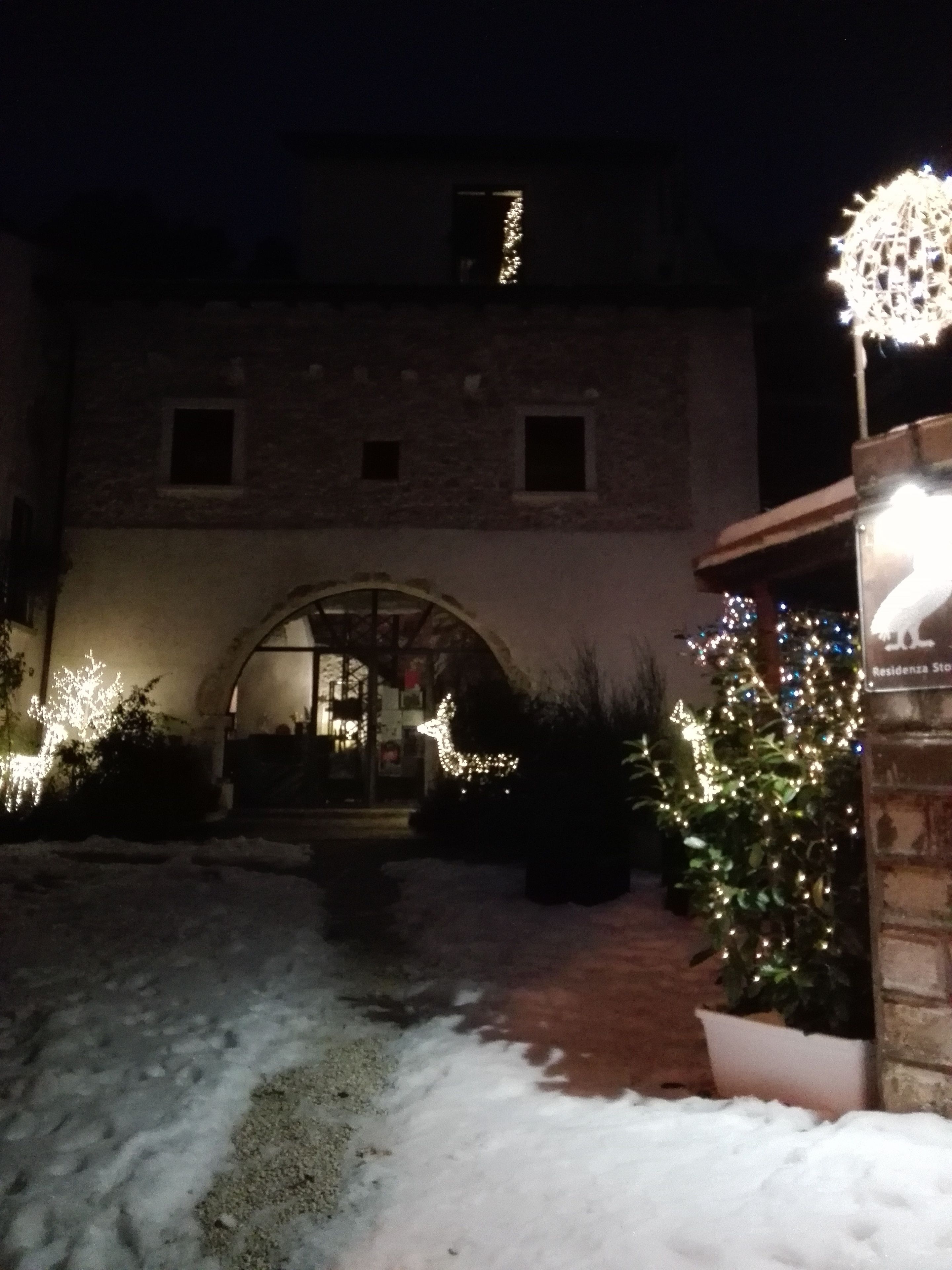 A building with a brick facade, an arched entrance, and a snow-covered ground.