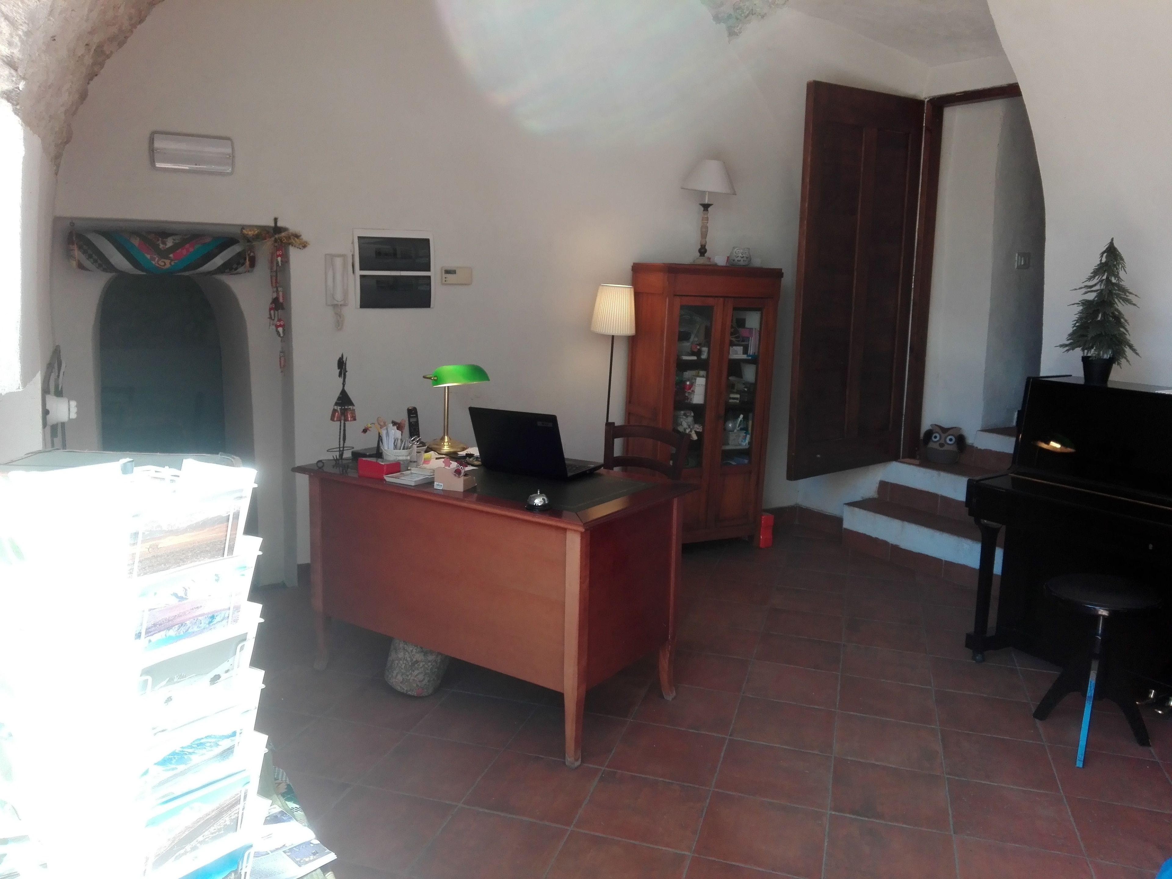 Une pièce comprenant un bureau, un piano, une lampe et un meuble.