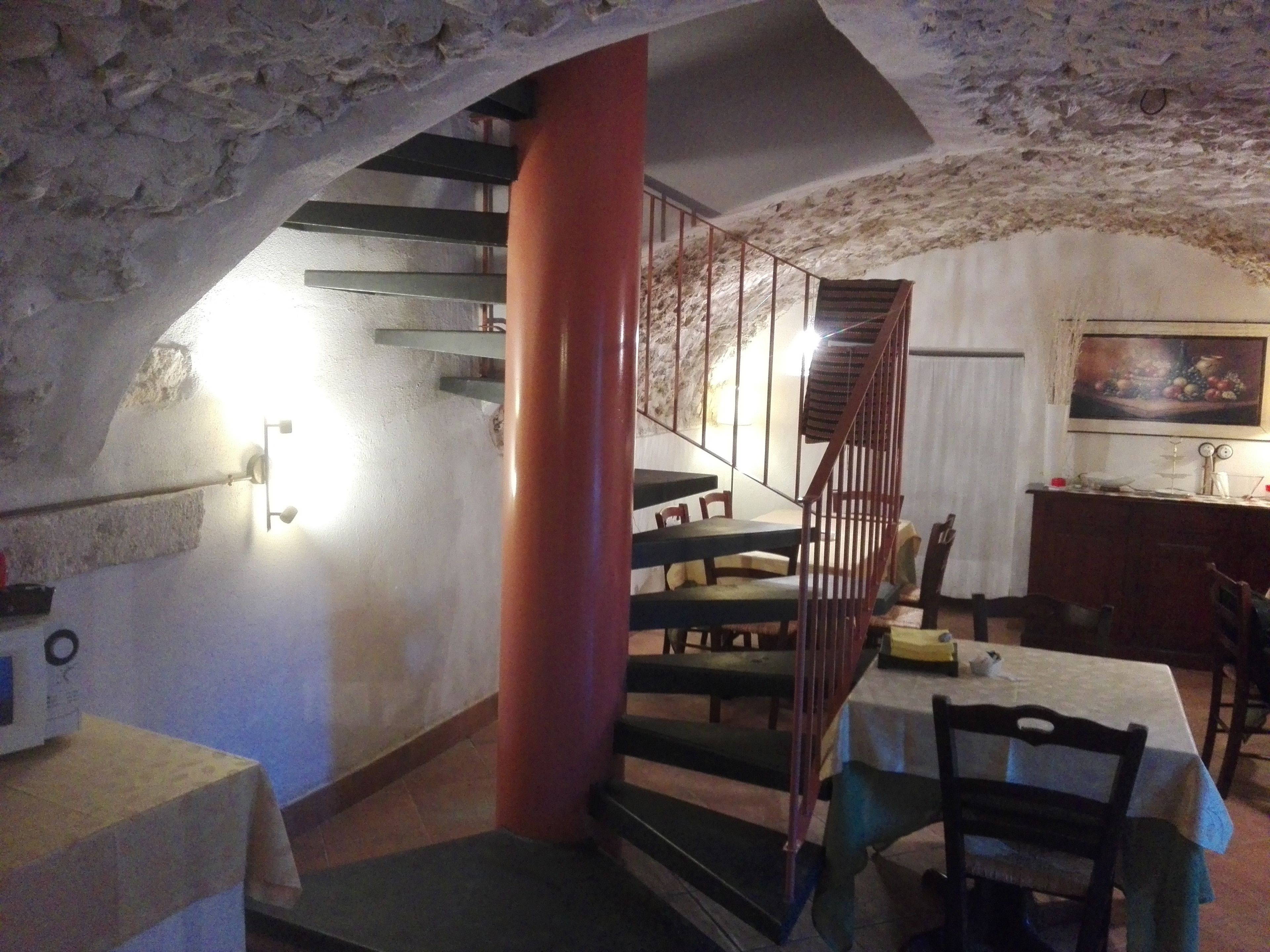 Een eethoek met een trap naar een lager gelegen niveau, een tafel met stoelen en een schilderij aan de muur.