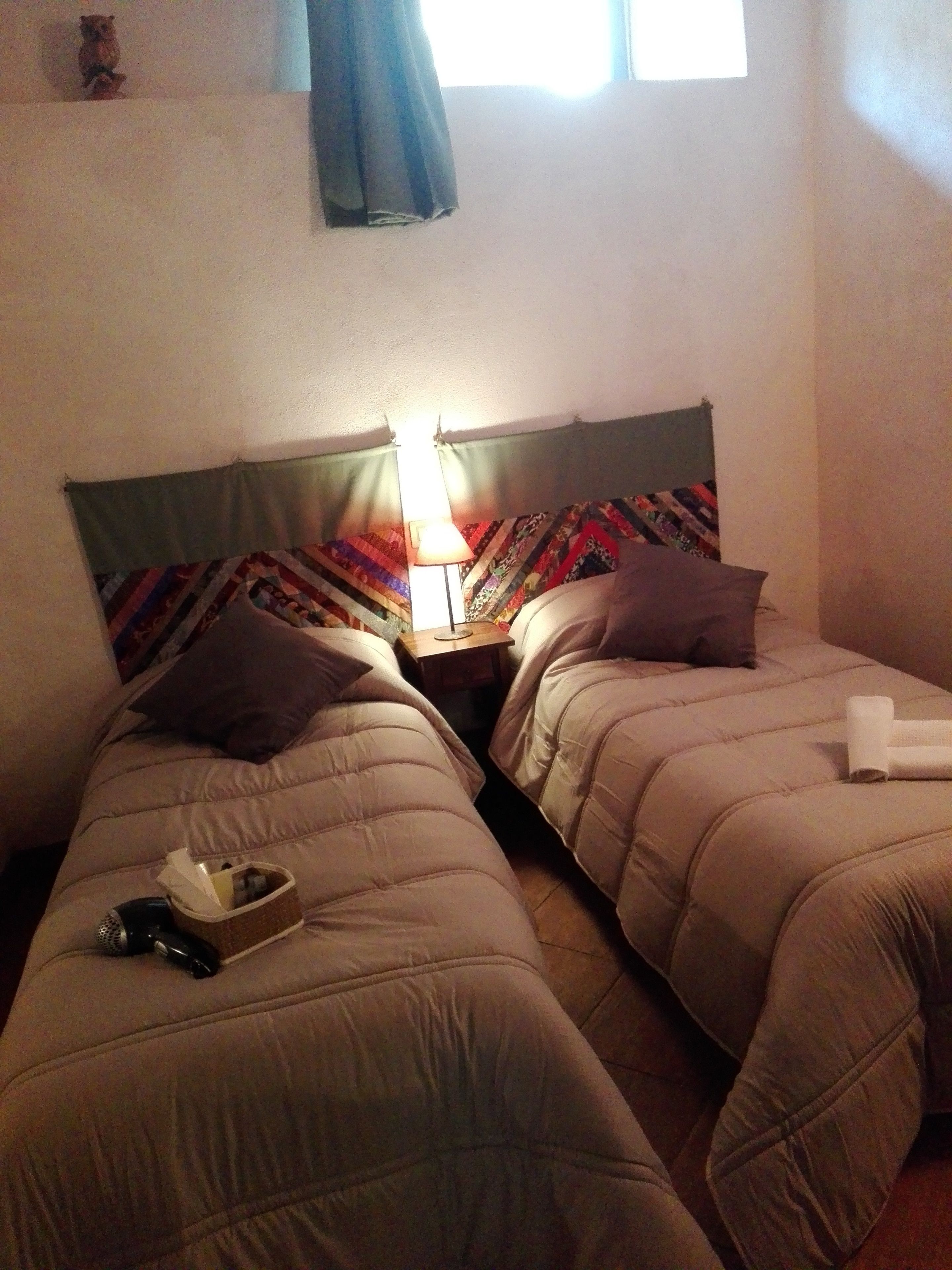 Deux lits simples avec des têtes de lit, une lampe de chevet et une couverture matelassée sur chaque lit.