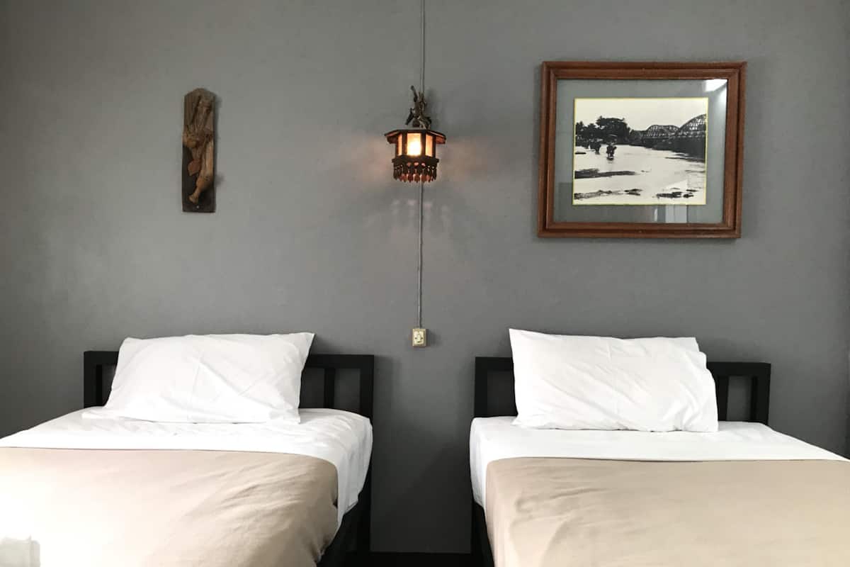 Een hotelkamer met twee bedden, een wandlamp, een lijst met een afbeelding en een houten decoratie aan de muur.
