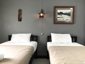 A room with two beds, a wall-mounted light fixture, and a framed picture. - Royal Night Bazaar Hotel (Chiang Mai)
