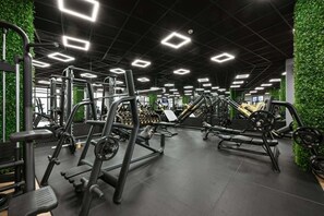 A gym with various exercise equipment, green walls, and a ceiling with square lights. - Grand Hotel Velingrad (Velingrad)