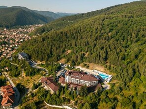 Un resort con piscina, rodeado de colinas cubiertas de bosque.