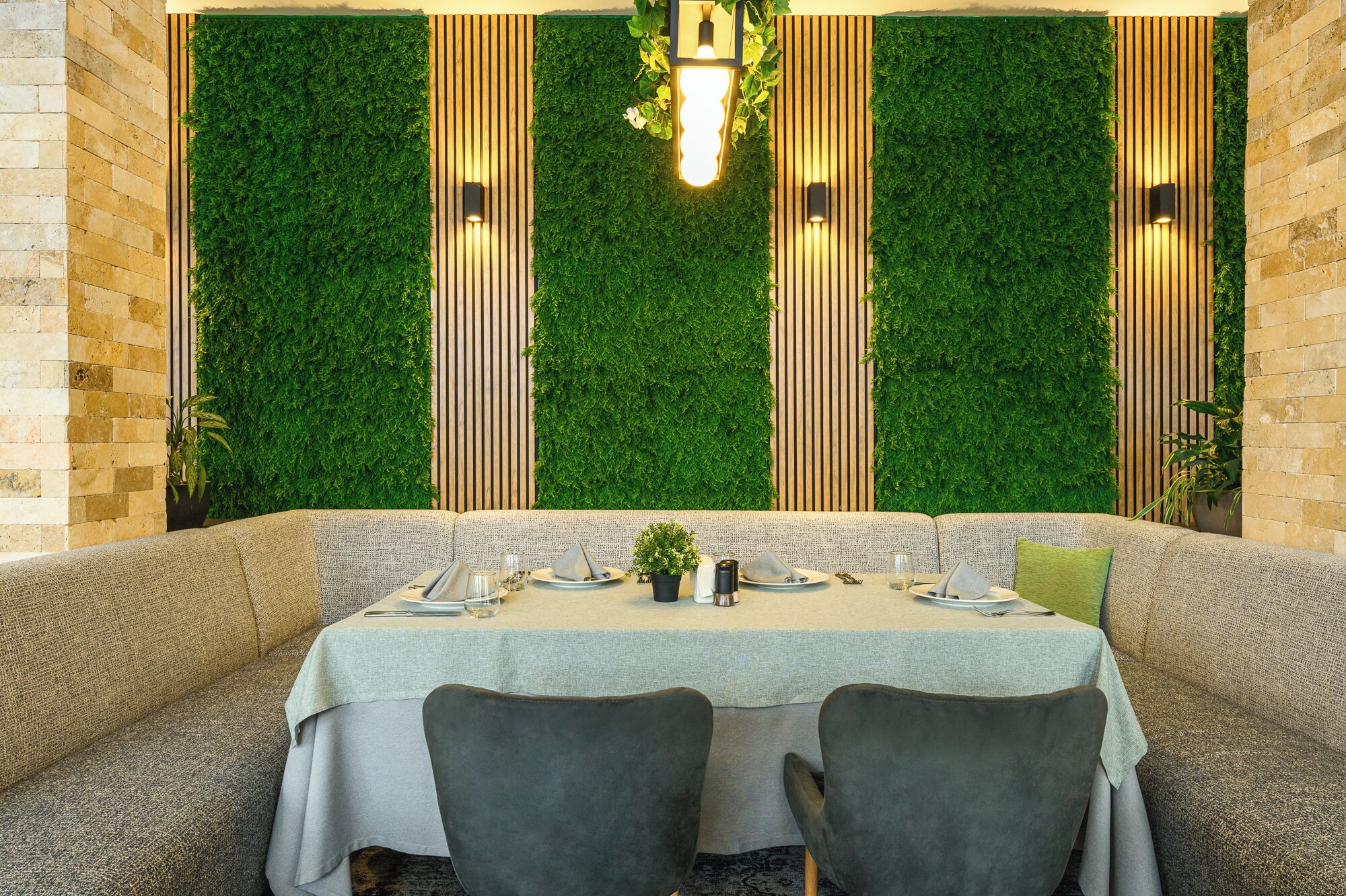 Un restaurante con una pared verde, listones de madera y una mesa lista para dos comensales.