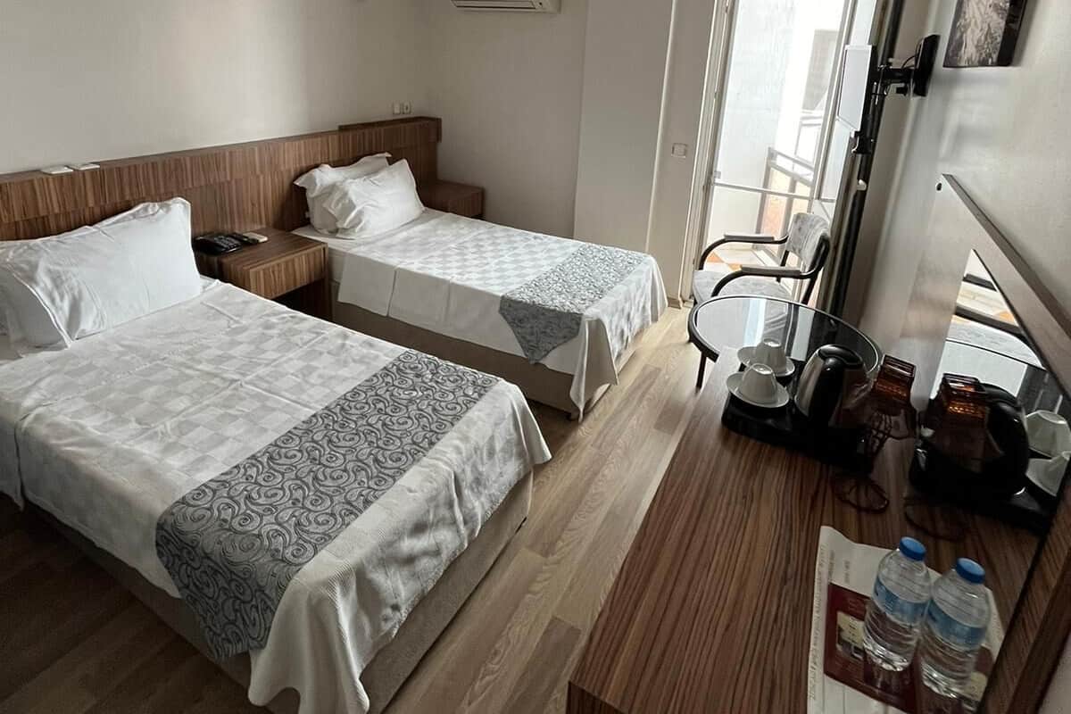 Une chambre d’hôtel avec deux lits, un bureau, une chaise, un appareil de climatisation et une fenêtre donnant sur un paysage agréable.