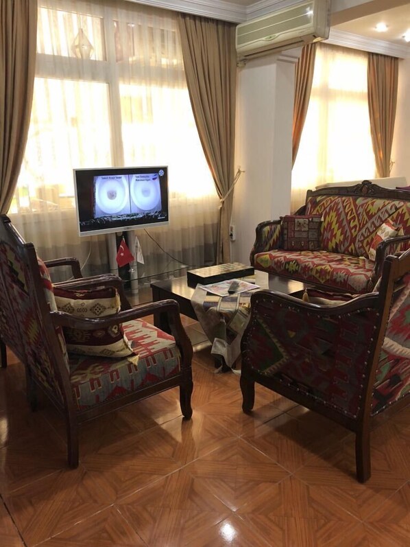 Una sala de estar con televisor, sofás estampados y una mesa de centro.