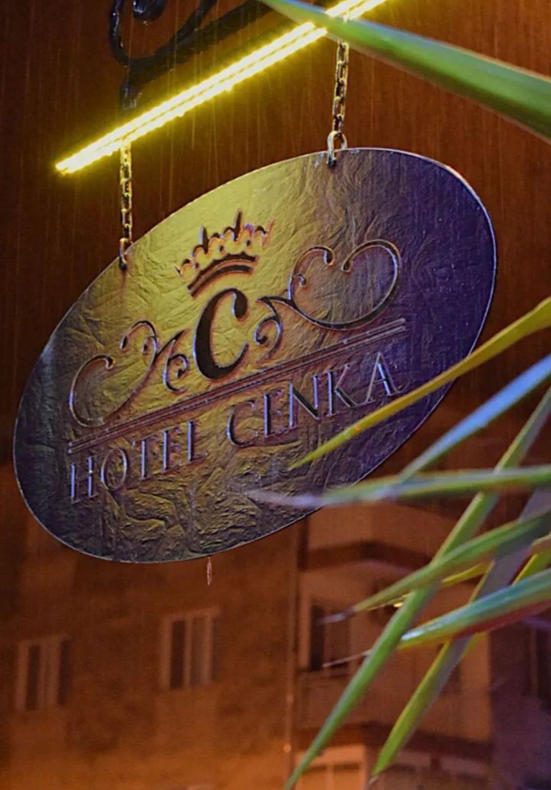 Un letrero con el texto 'HOTEL CINKA' y un símbolo de corona, que indica un establecimiento hotelero.